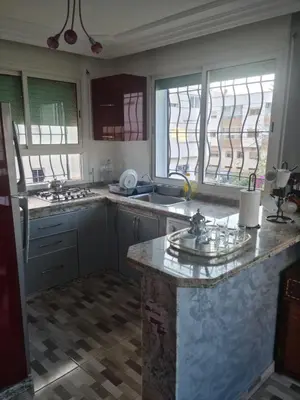 a kitchen with a counter and two sinks and windows at Belle maison à Harhoura proche de la plage in Rabat