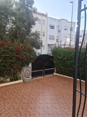 a courtyard with a black umbrella and some bushes at Belle maison à Harhoura proche de la plage in Rabat