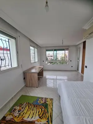 a bedroom with a bed and a desk and windows at Belle maison à Harhoura proche de la plage in Rabat