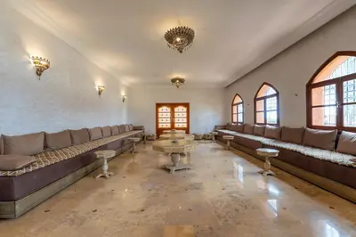 a waiting room with couches and a table and windows at Château Loriana in Bouznika