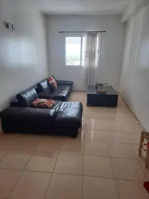 a living room with a black leather couch and a window at Moonskhirat in Skhirat