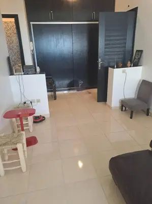a living room with a black door and a table and chairs at Moonskhirat in Skhirat