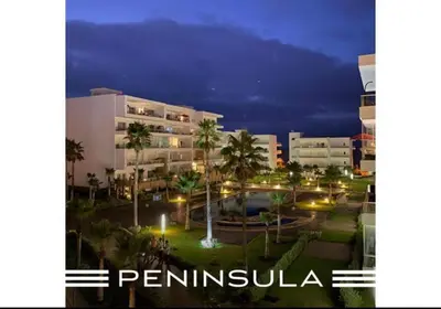 a building with a pool and palm trees at night at Appartement pied sur mer- resid férmé- pscine in Tamaris