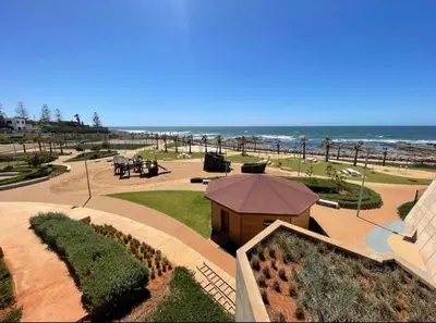a view of a park with the ocean in the background at Appartement pied sur mer- resid férmé- pscine in Tamaris