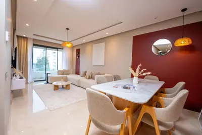 a dining room with a table and a living room at Prestigia Gem Spacious 3BR Flat in Hay Riad in Rabat