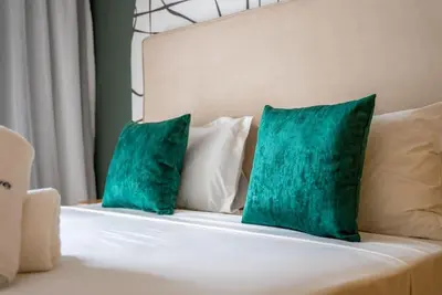 two green pillows sitting on a white bed at Prestigia Gem Spacious 3BR Flat in Hay Riad in Rabat