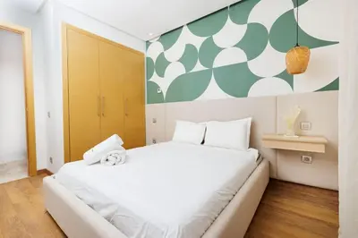 a bedroom with a white bed with a green and white wall at Luxury 3BR Homelike Stay in Hay Riad in Rabat