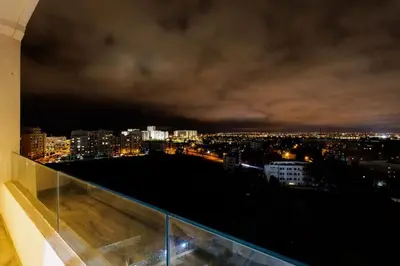 a view of a city at night from a balcony at Luxury 3BR Homelike Stay in Hay Riad in Rabat