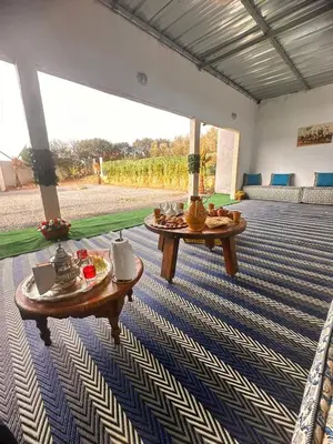 a living room with two tables on a carpet at Ferme de luxe in O Ben Slimane
