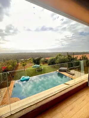 a swimming pool in a house with a large window at Ferme de luxe in O Ben Slimane
