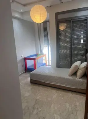 a bedroom with a bed and a table and lights at Appartement de luxe à Casablanca in Aïn Sebaa
