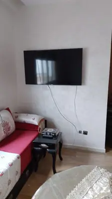 a living room with a couch and a tv on the wall at émeraude house family in Casablanca