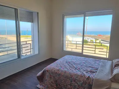 a bedroom with two windows and a bed with a view of the ocean at Apartment Ocean View 2Br in Casablanca