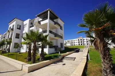 a white building with palm trees in front of it at Apartment Ocean View 2Br in Casablanca