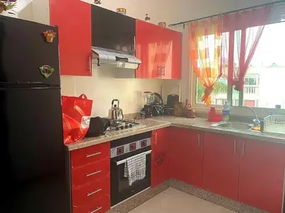 a kitchen with red cabinets and a black refrigerator at Appartement, Salam Beach in Pont Blondin