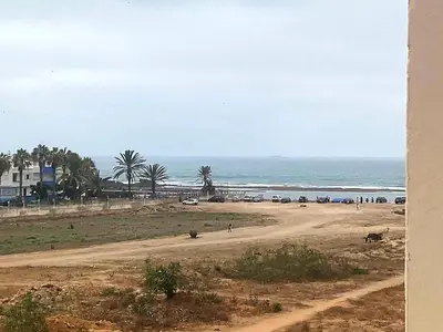 a beach with cars and people on a dirt road at Appartement, Salam Beach in Pont Blondin