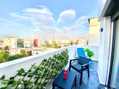 a balcony with two chairs and a view of a city at Confort & Charme à Casablanca in Maarif