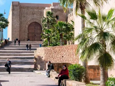 two people sitting on a bench in front of a building at ONOMSUIT-Appartement en plein centre ville RABAT in Rabat
