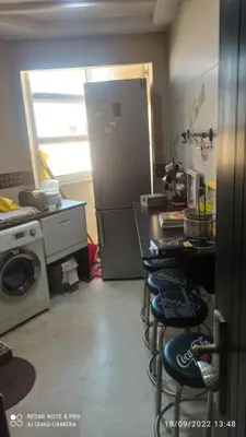 a kitchen with a refrigerator and four bar stools at Appartement haut standing in Casablanca