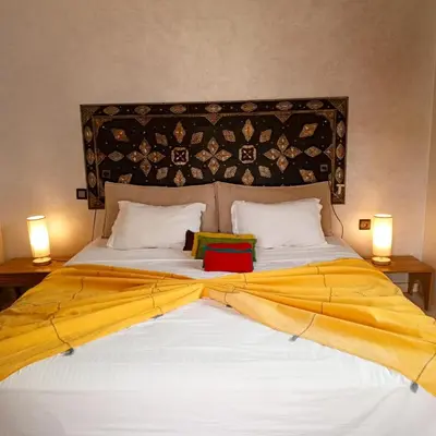 a large bed with a yellow blanket on it at Espace happy village settat in Settat