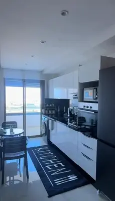 a kitchen with white cabinets and a table and a dining room at أجمل شقة الوفاق in Temara