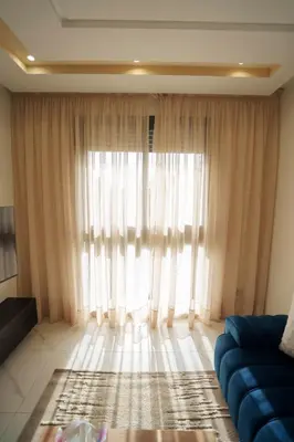 a living room with a blue couch and a large window at Emplacement Central Lumineux & Chic Prés de Station Tramway KFC Et Carrefour Abdelmoumen Et 2 Mars Casablanca in Casablanca