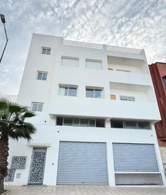 a white building with two garage doors at Ksar Labhar City Escape in Rabat