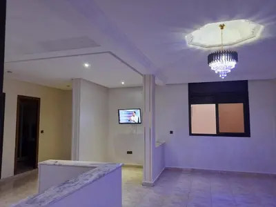 a living room with a chandelier and a wall at Apartament Ines in Skhirat