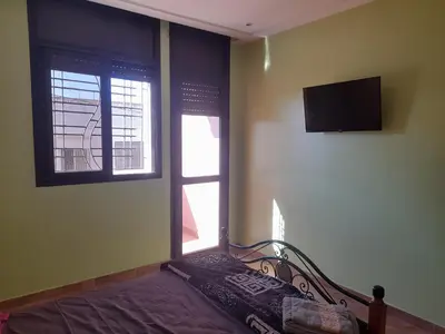 a bedroom with a bed and a tv on the wall at Apartament Ines in Skhirat