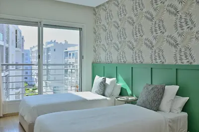 a hotel room with two beds and a window at YourPlace - Modern, Spacious 3BR in Prestigia in Rabat
