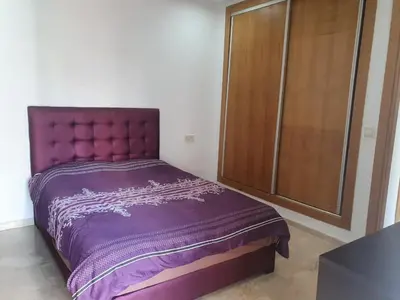 a purple bed in a room with a large window at Superbe Appartement pieds dans l'eau Résidence Garden Bay in Sidi Rahal