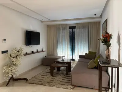 a living room with a couch and a tv at Modern minimaliste retreat in Maarif in Casablanca