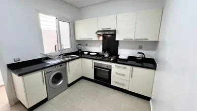 a kitchen with white cabinets and a washer and dryer at N8 appartement, 3 Chambres Haut de Gamme, a Deux Pas de l Ocean et du Mall in Rabat