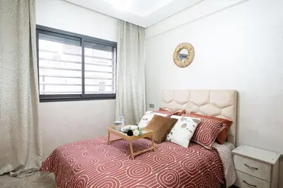 a bedroom with a bed with a table on it at Chic 2 chambres balcon vue panoramique et piscine in Aïn Harrouda
