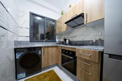 a kitchen with a sink and a dishwasher at Chic 2 chambres balcon vue panoramique et piscine in Aïn Harrouda