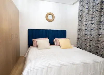 a bedroom with a large bed with a blue headboard at Chic 2 chambres balcon vue panoramique et piscine in Aïn Harrouda