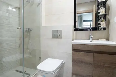 a bathroom with a shower and a toilet and a sink at Chic 2 chambres balcon vue panoramique et piscine in Aïn Harrouda