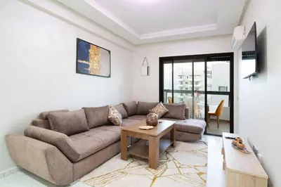 a living room with a couch and a table at Chic 2 chambres balcon vue panoramique et piscine in Aïn Harrouda