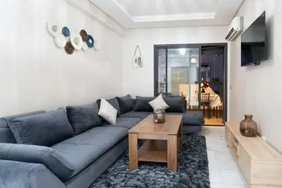 a living room with a blue couch and a table at Magnifique 2 chambres, vue panoramique et piscine in Casablanca