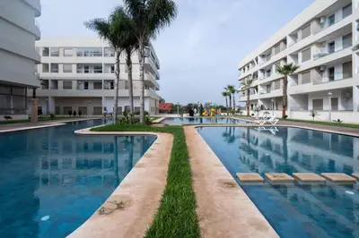 a swimming pool in front of a building at Appartement avec Piscine Proche Plage in Bouznika