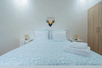 a white bedroom with a bed with towels on it at Appartement avec Piscine Proche Plage in Bouznika