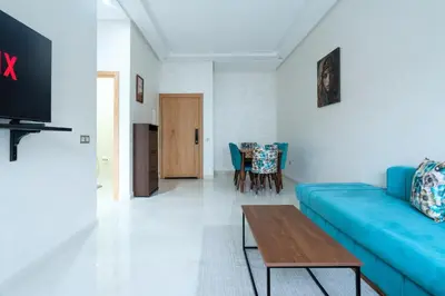 a living room with a blue couch and a table at Appartement avec Piscine Proche Plage in Bouznika