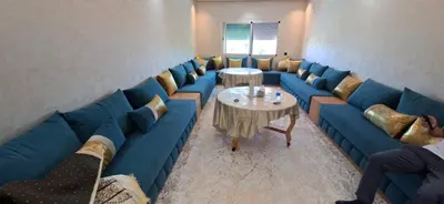 a waiting room with blue couches and a table at Residence la corniche d in Mohammedia