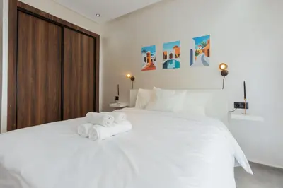 a bedroom with a white bed with towels on it at Appartement cosy et moderne Bouskoura proche Aéroport et Hopital universitaire in Bouskoura