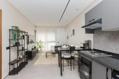 a kitchen with a table and chairs in a room at Appartement cosy et moderne Bouskoura proche Aéroport et Hopital universitaire in Bouskoura