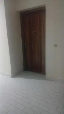 a room with a wooden door and a white tile floor at best location single room in Casablanca