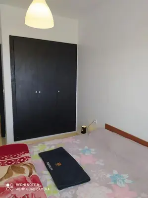 a bedroom with a bed and a black cabinet at Appartement neuf tres calme balcon vue sur l'océan in Skhirat
