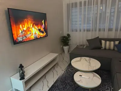 a living room with a couch and a fire on the wall at Magnificent Cozy New Luxury Condo in Prime Casablanca Location in Les Camps