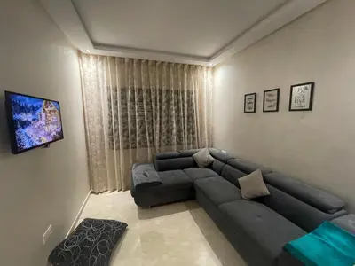 a living room with a couch and a television at Luxury 3 Bedroom Apt Near Park and Sea, Heated Indoor Pool, Wifi, Free Parking in Casablanca