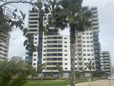 a tall building with a palm tree in front of it at Luxury 3 Bedroom Apt Near Park and Sea, Heated Indoor Pool, Wifi, Free Parking in Casablanca